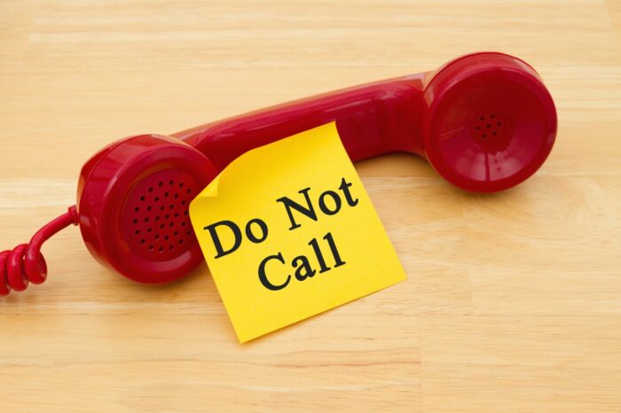 Getting on the do not call list, Retro red phone handset with a yellow sticky note and text Do not call