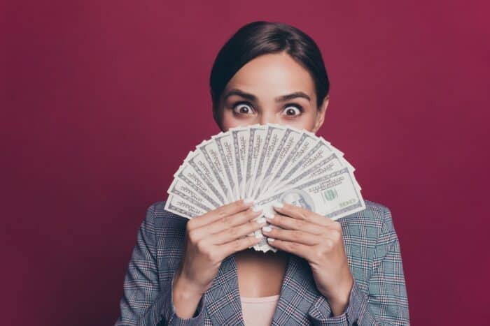 Cash in hand happy excited female with dark hair on maroon background