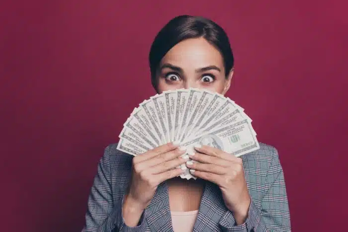 Cash in hand happy excited female with dark hair on maroon background