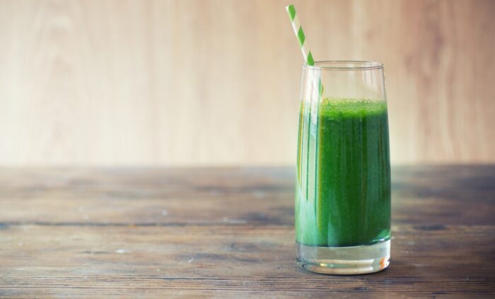 Green drink in glass with green-and-white straw - All Day Energy Greens lawsuit - bactolac - NaturMed