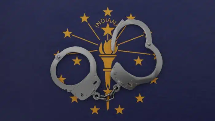 rendering of a half opened steel handcuff in center on top of the US state flag of Indiana - jail settlement