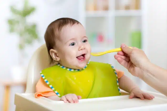 baby eating food on kitchen