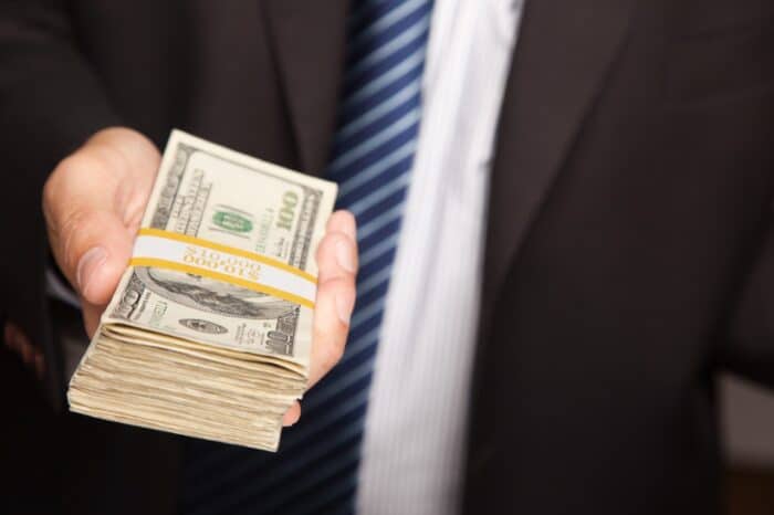 Businessman Handing Over Stack of One Hundred Dollar Bills.