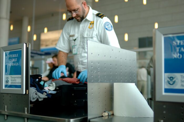 A TSA agent searches luggage at an airport.