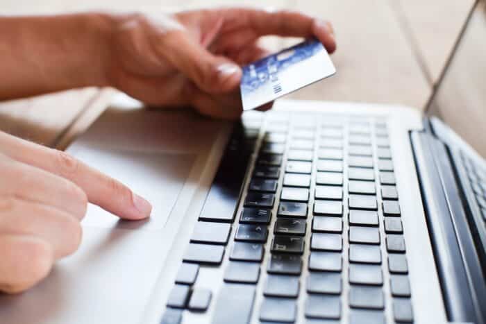A person uses a credit card to make a purchase on their laptop - stubhub fees - stubhub class action - stubhub settlement wang