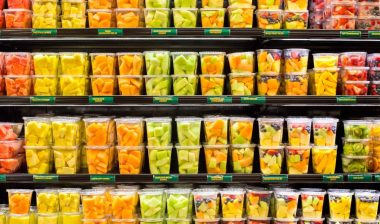 supermarket grocery display case with fresh cut fruit on shelves in plastic containers