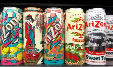 Grocery store shelf with 23 ounce cans of Arizona brand ice teas in various flavors.