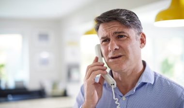 Frustrated Mature Man Receiving Sales Call At Home