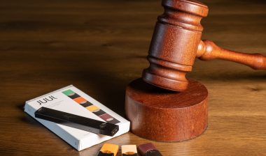 Juul e-cigarette or nicotine vapor dispenser box with Judge's gavel for lawsuit.