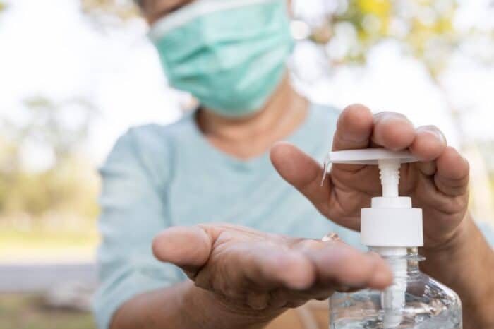 Asian elderly people wearing protective mask,using alcohol hand sanitizer - Sugarmill Distillery