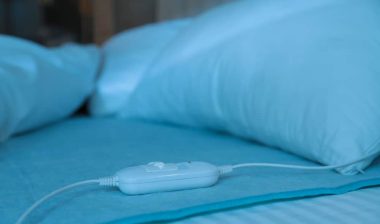 Bed with electric heating pad indoors at night.