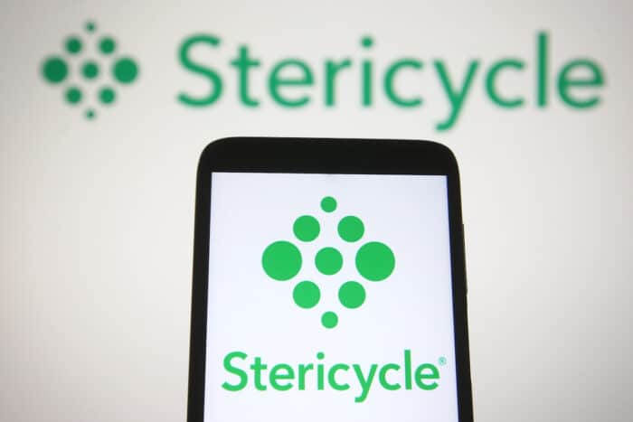In this photo illustration Stericycle, Inc. logo is seen on a mobile phone and a computer screen.
