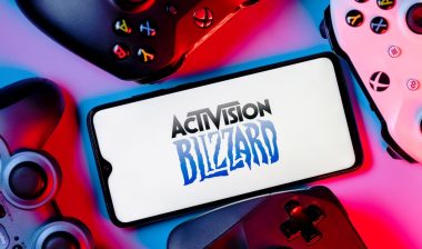 A smartphone with the Activision Blizzard logo on the screen surrounded by gamepads.