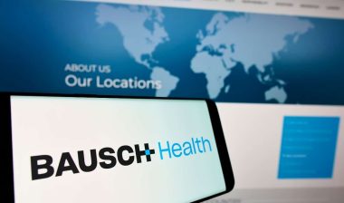 Mobile phone with logo of pharmaceutical company Bausch Health Companies Inc on screen in front of website