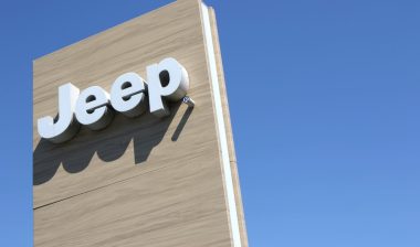 Jeep dealership sign against blue sky.