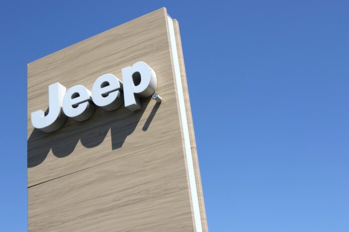 Jeep dealership sign against blue sky.