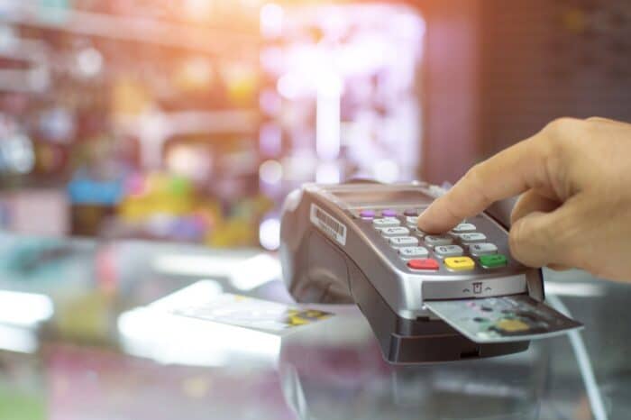 A person enters their PIN on a credit card reader - central payment fees lawsuit settlement administrator