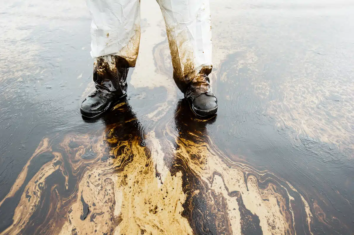 Photo of a worker standing on an oil spill.