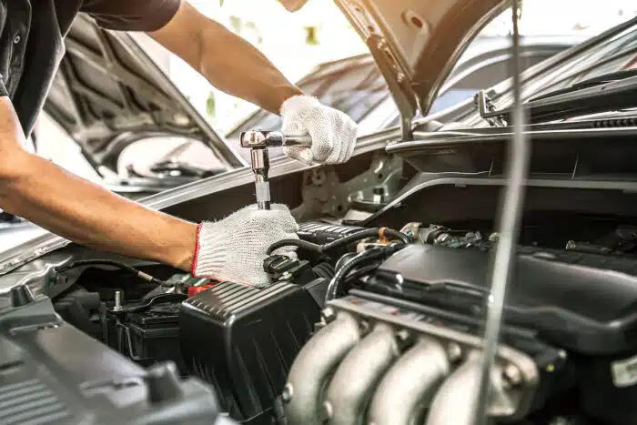Close-up hands of auto mechanic are using the wrench to repair and maintenance auto engine is problems at car repair shop.