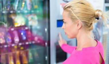 woman wearing pink using a modern vending machine.