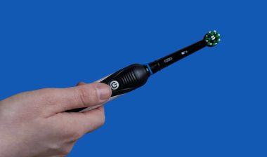 Closeup of Electric toothbrush Oral-B black edition on blue background.