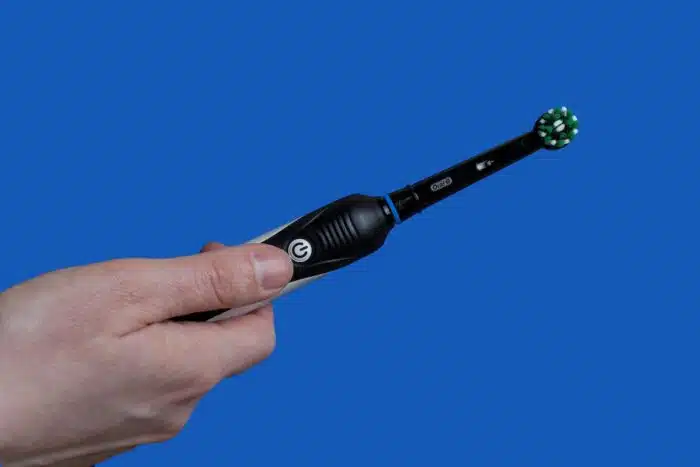 Closeup of Electric toothbrush Oral-B black edition on blue background.