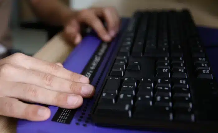 Blind person using computer with braille computer display and a computer keyboard - visually impaired - avocado mattress class action
