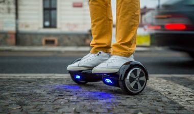 Photo of man using a hoverboard against the background of leaving car.