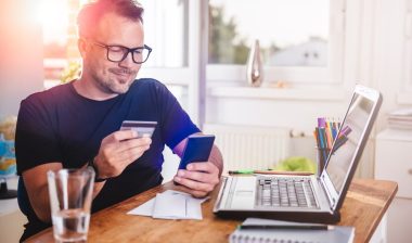 Man paying with credit card on smart phone at home office