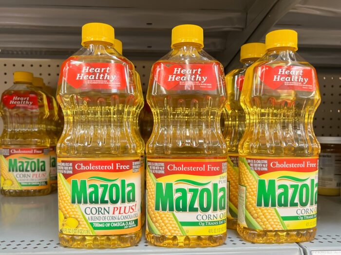 Mazola corn oil and Mazola Corn Plus oil on a grocery shelf.