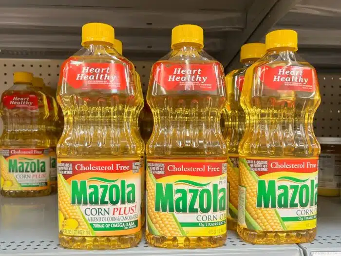 Mazola corn oil and Mazola Corn Plus oil on a grocery shelf.