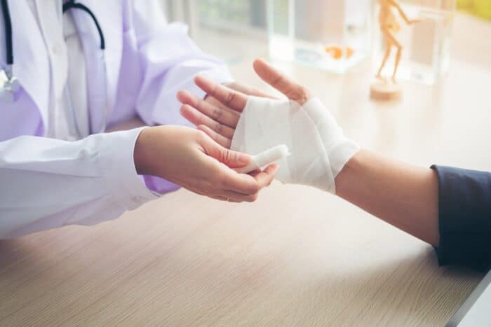 First aid and treatment in wrist injuries and disorders, Traumatologist is taking care of the patient, woman doctor bandaging a hand.