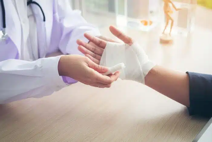 First aid and treatment in wrist injuries and disorders, Traumatologist is taking care of the patient, woman doctor bandaging a hand.