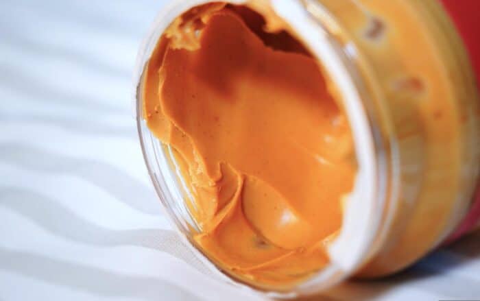 Open peanut butter jar close up on table.