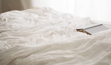 A book on a bed with sheets.