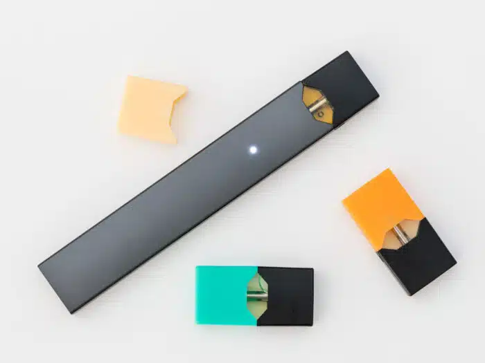 Juul e-cigarette or nicotine vapor stick and JUULpods on white background.