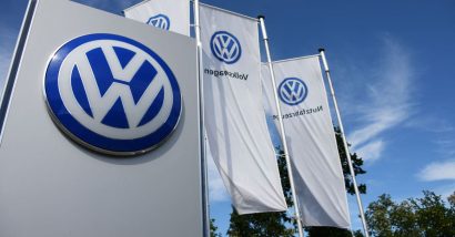Flags and VW logo against blue sky.