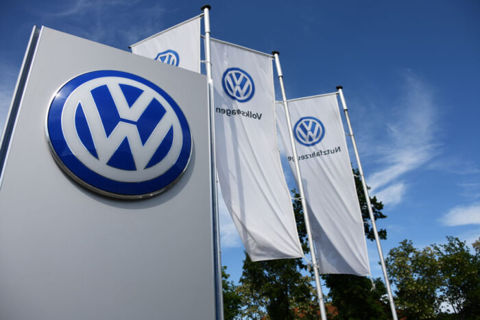 Flags and VW logo against blue sky.