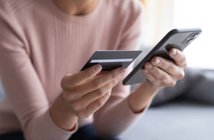 Close up female hands holding credit card and smartphone.
