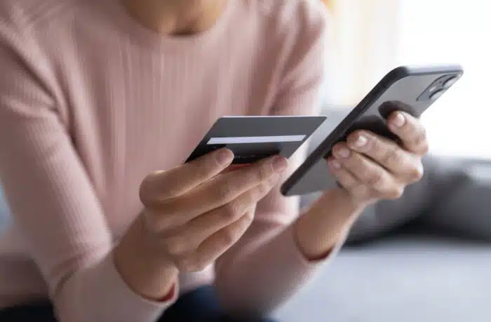 Close up female hands holding credit card and smartphone.