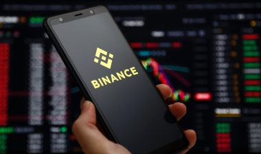 Binance mobile app running at smartphone screen with a trading page at background.