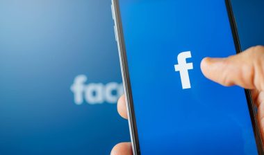 Phone showing facebook app on the screen. Facebook is a photo sharing social media desktop background.