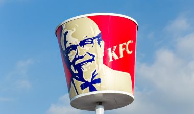 Traditional KFC restaurant sign against a bright blue sky.