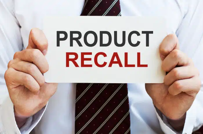A businessman holding a sign that reads 'product recall'