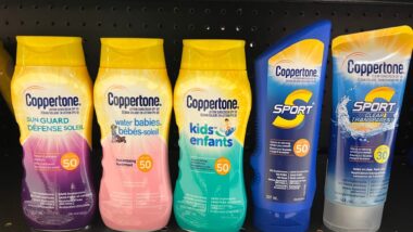 Bottles of various types of Coppertone sunscreen on a pharmacy shelf.