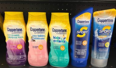 Bottles of various types of Coppertone sunscreen on a pharmacy shelf.