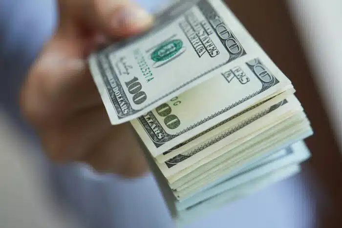 Close up of a hand holding hundred dollar bills.