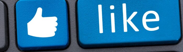 Blue thumbs-up and "like" button on a black computer keyboard - facebook user tracking
