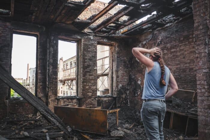 man holds his head by hand and cry in burnt out house after disaster. California catastrophic loss investigation