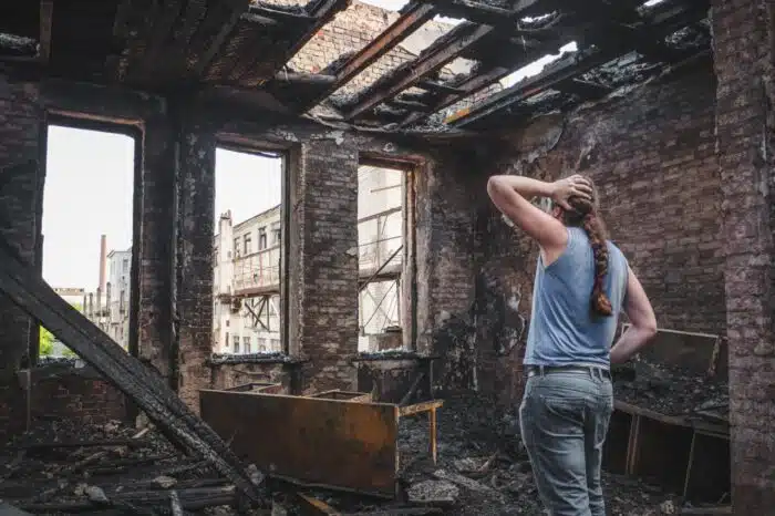 man holds his head by hand and cry in burnt out house after disaster. California catastrophic loss investigation